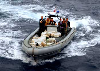 Sailors and Coast Guardsmen transport bales of cocaine seized from a boat in the Caribbean Sea